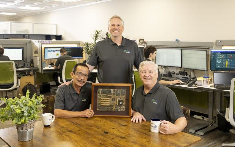Richweb's founders holding the framed motherboard from the company's first server